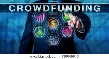 Entrepreneur in blue business suit is touching the catch word CROWDFUNDING on an interactive control monitor. Metaphor for collaborative finance internet terminology and payment system concept.