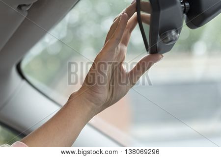 girl adjusts the rear view mirror in a car