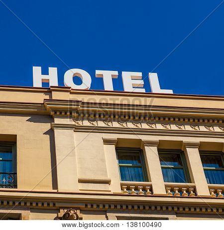 A modern hotel sign on building with classic arquitecture under a deep blue sky.