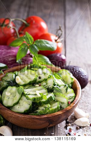 Pickled cucumber with dill and garlick in a rustic wooden bowl