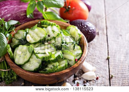 Pickled cucumber with dill and garlick in a rustic wooden bowl