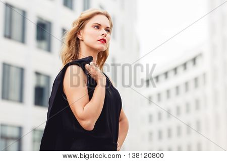 Closeup portrait in profile of beautiful intelligent woman with blonde wavy hair on business centre background. Split toned photo