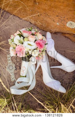 Picture of female white wedding shoes with a bouquet