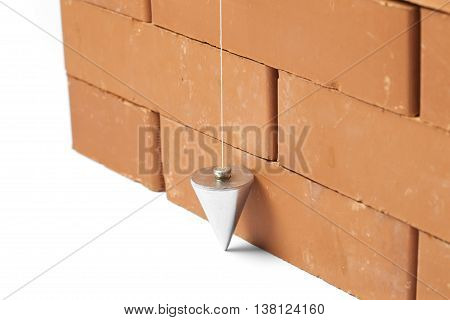 Bricks in masonry with touched plum bob for vertical line isolated on white background