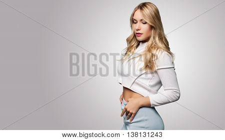 Young Sexy Model With Athletic Body. Beautiful Woman In Stylish Clothes On A Gray Background. Blonde