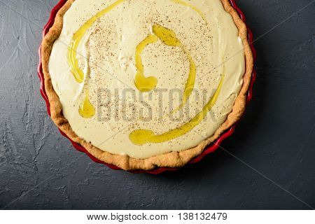 Close-up photo of tart with cream and olive oil, prepared for baking, over textural gray surface