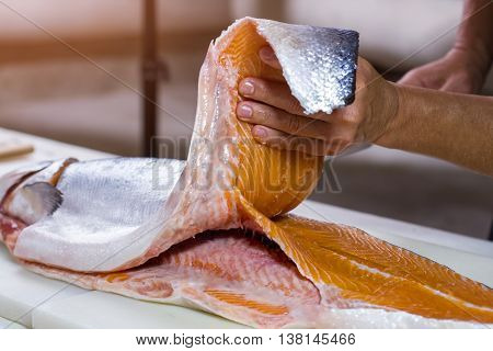 Man's hand holds fish meat. Meat of raw fish. Best salmon for cooking sushi. Lots of calories and protein.