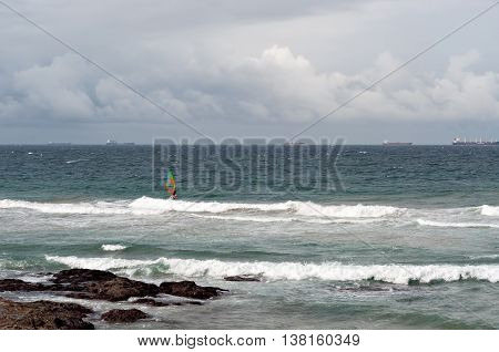 DURBAN SOUTH AFRICA - JULY 09 2016: Windsurfers in the waves at Umhlanga Rocks with shipping on the Indian Ocean in the background.