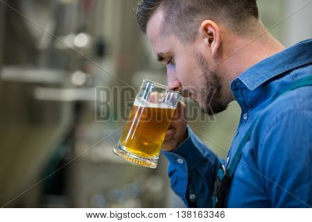 Close-up of brewer testing beer at bewery