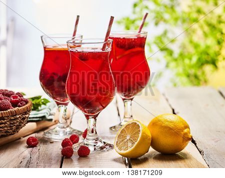 Wooden boards are ice cold beverage glasses with red raspberry lemon cocktail . Alcohol country cocktail beverage number hundred thirty six with raspberry basket. Cocktail beverage corporate outdoor.