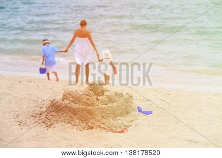 mother and two little kids play with sand on beach