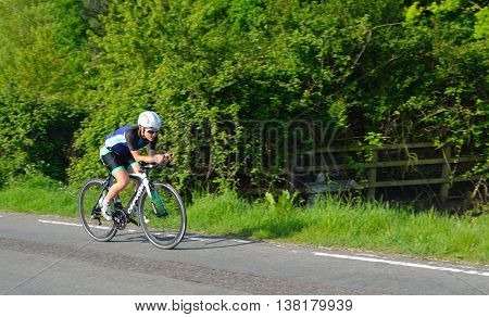 Grafham, Cambridgeshire, England - May 22, 2016:  Female triathlon  competitor on road cycling stage.