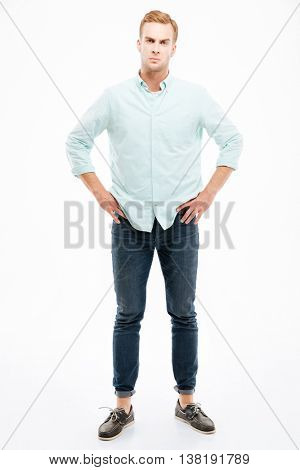 Full length of angry strict young man standing with hands on hips over white background