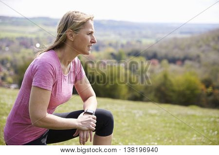 Mature Woman Checking Activity Tracker Whilst On Run