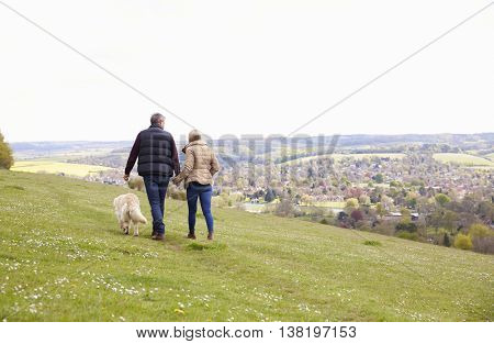 Rear View Of Mature Couple Taking Golden Retriever For Walk
