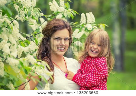 Outdoor portrait of happy mother and daughter in bloomimg flowers