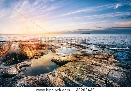 Stone coast of Ladoga lake at sunset. Karelia, Russia.