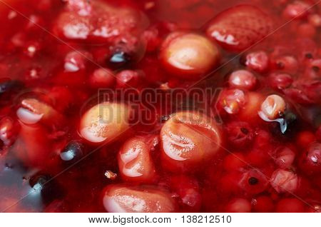 Multifruit compote during boiling. Colorful fruit background