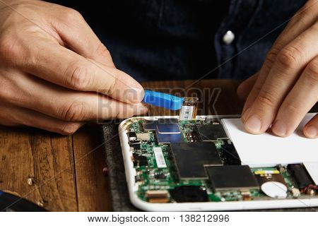 Pro uses special plastic opener to unclip electronic cord from motherboard in gadget Repairing and fixing service in lab