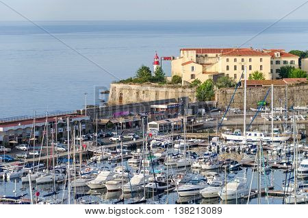 Ajaccio France - May 27 2016: View of the center of capital city of Corsica and birthplace of Napoleon Bonaparte with its marina Fishing Port water front and the lighthouse of the citadel overlooking the bay.