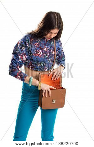 Woman opens brown handbag. Bright pants and crop top. All things in place. Stylish look for summer.