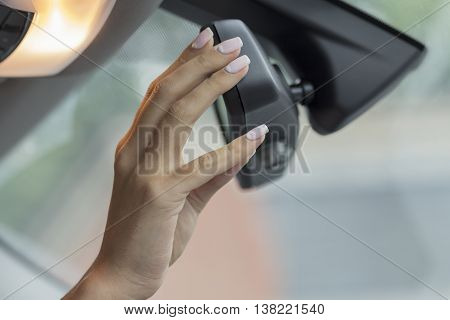 the girl in the cabin of the car  adjusts the rear view mirror