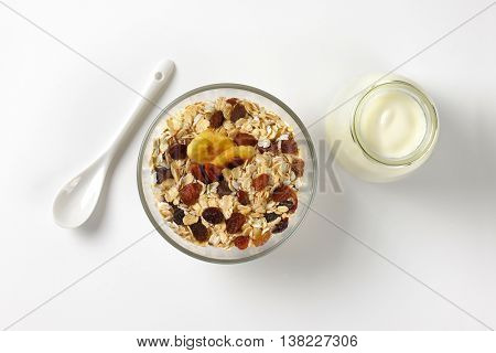 bowl of oat flakes and glass of white yogurt on off-white background with shadows