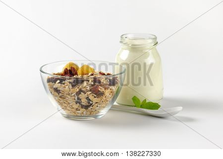 bowl of oat flakes and glass of white yogurt on off-white background with shadows