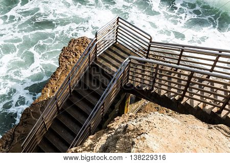 Bottom of beach access staircase at high tide, Ladera Street, Sunset Cliffs, San Diego, California.