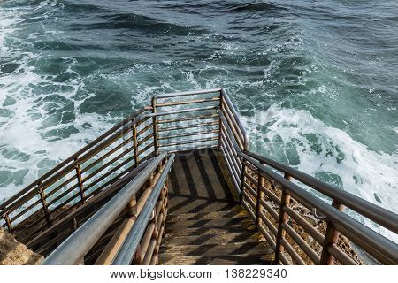 Lower level of beach access staircase at high tide, Ladera Street, Sunset Cliffs, San Diego, California.