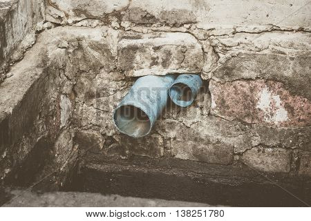Blue PVC water pipe in dirty underground sewer for dredging drain tunnel cleaning selective focus (vintage effect)