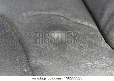 A dent pressure mark indentation on old leather vehicle car seat with selective focus