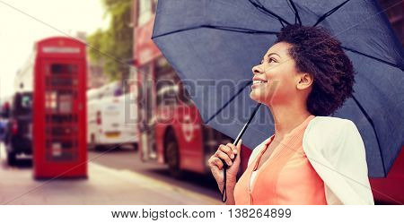 weather, travel, tourism, citylife and people concept - young smiling african american woman with umbrella over london city street background