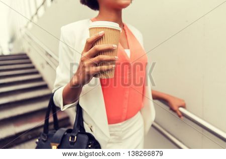 business, drinks, lifestyle and people concept - close up of young african american businesswoman with coffee cup walking downstairs to city subway