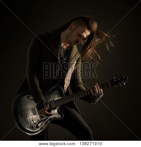 Guitarist playing rock music. On dark background. Beautiful guitar.