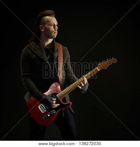 Guitarist playing rock music. On dark background. Beautiful guitar.