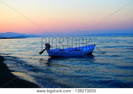 Blue boat in Messonghi at colourful sunset in Corfu, Greece.