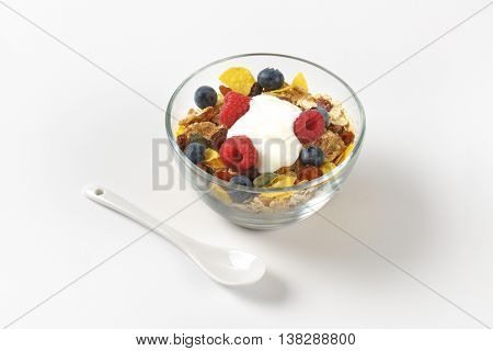 bowl of cereals with berry fruit and white yogurt on off-white background with shadows