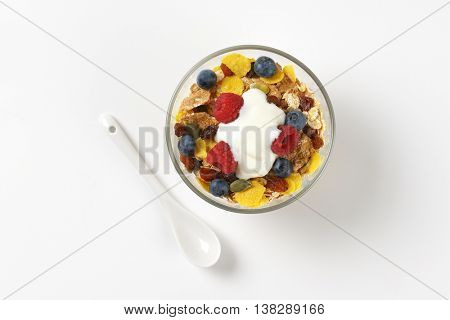 bowl of cereals with berry fruit and white yogurt on off-white background with shadows