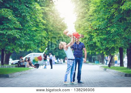 Young happy family of three having fun together outdoor. Pretty little daughter on her father back. Parents and girl look happy and smile. Happiness and harmony in family life. Family fun outside.