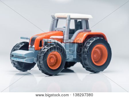 Small red toy tractor on light background, shallow depth of field