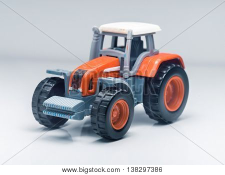 Small red toy tractor on light background, shallow depth of field