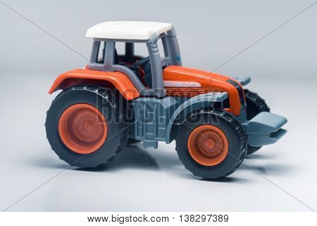 Small red toy tractor on light background, shallow depth of field