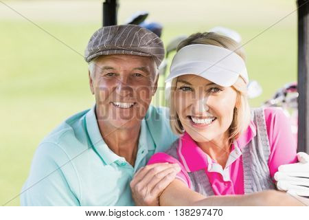 Portrait of cheerful golfer couple sitting in golf buggy