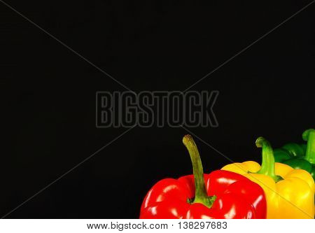 3 bright peppers on a black background: red, green, yellow