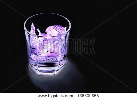 alcoholic cocktail with mint, lemon and gin in ultraviolet light