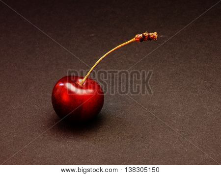 elegant red cherries lie on a black surface