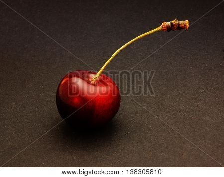 elegant red cherries lie on a black surface