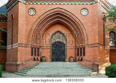 Massive wooden church door with a handle forged with an iron grip settled into a brick wall at the church. Breclav. South Moravia
