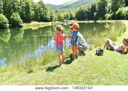 Daddy with kids fishing together by mountain lake